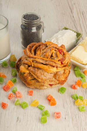 Cake with candied fruits on a wooden background and ingredients