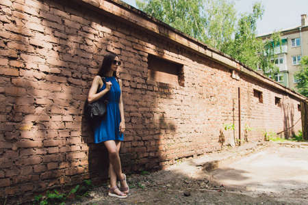 A very beautiful and cheerful girl stands on the street near a brick wallの写真素材