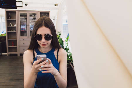 A very beautiful girl is sitting in a cafe in black round glassesの写真素材