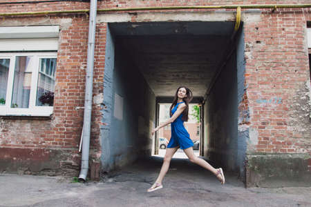 A very beautiful and cheerful girl jumps near the passage from the courtyardの写真素材