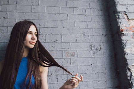 A very beautiful and cheerful girl stands on the street with long, luxurious hairの写真素材