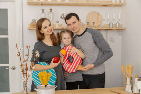 Fun and beautiful family of three having fun in the kitchen.