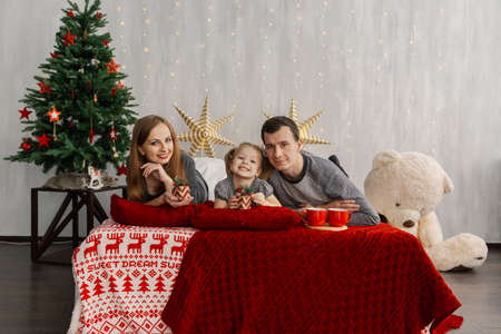 Happy family on bed on a bright Christmas morning. New Year 2019.