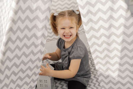 A girl plays in a tepee with toys.の写真素材
