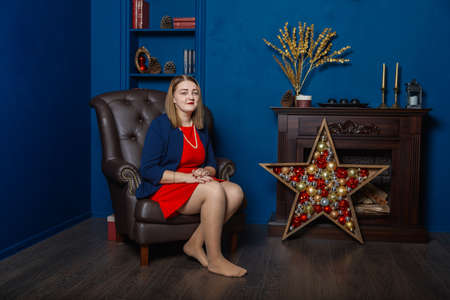 Very beautiful woman stands near the fireplace in the New Years room.の写真素材