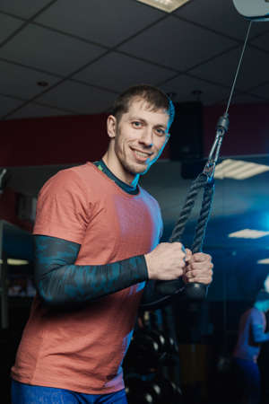 Handsome athletic man trains triceps on the block in the gym.