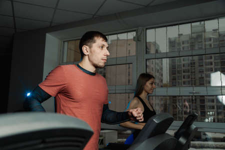 Active beautiful fitness model girl and athletic man train on the treadmill in the gym.の写真素材
