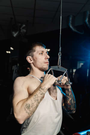 Handsome athletic man working out on the gym machine in the gym.