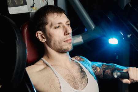 Handsome athletic man trains pectoral muscles on a simulator in the gym.の写真素材