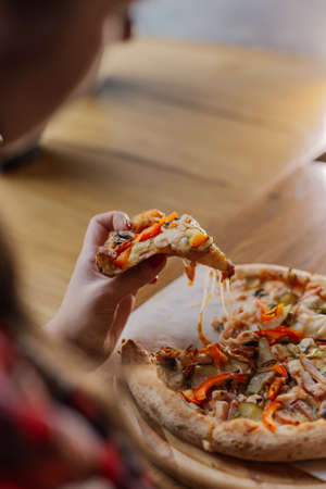 Beautiful and sexy girl sitting by the window in a cafe and eating pizza.の写真素材
