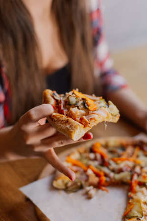 Beautiful and sexy girl sitting by the window in a cafe and eating pizza.の写真素材
