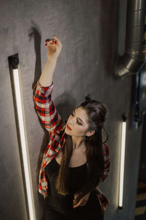Beautiful and sexy girl posing for a photographer on the black iron stairs with lamps in a cafe.の写真素材