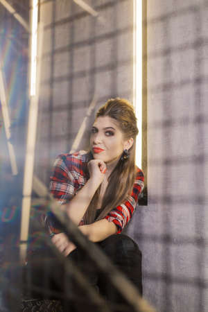 Beautiful and sexy girl posing for a photographer on the black iron stairs with lamps in a cafe.の写真素材