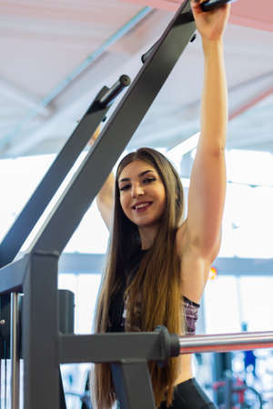 Young woman training in the gym. Pulling in gravitrone.の写真素材