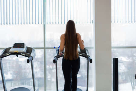Attractive young sports woman is working out in gym. Doing cardio training on curve treadmill. Running on non-motorized treadmill.の写真素材