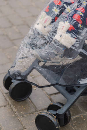 A woman walks in the park with a stroller and a small child.