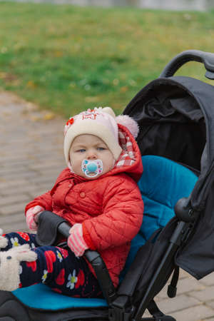 The little baby is sitting in the pram.