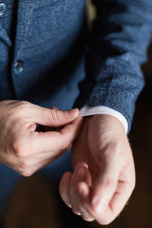 Businessman in a white shirt straightens cuffs, standing at the window in natural light. Man buttons cuff-link on French cuffs sleeves luxury white shirt. Concept successfully bisinesmanの写真素材