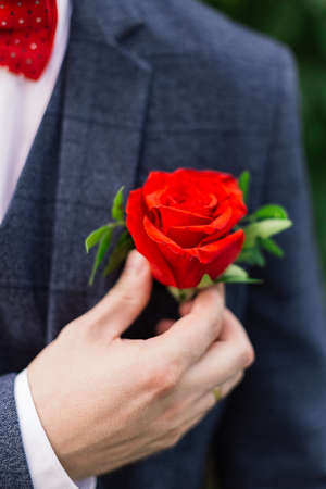 The groom straightens the boutonniere of flowers on his jacket.の写真素材