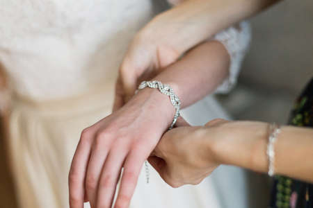 bride putting on luxury bracelet on hand in the morning, getting ready.の写真素材