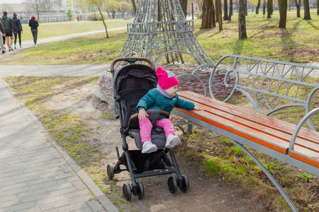 Little girl sitting in a baby carriage on the streetの写真素材