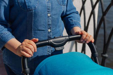 The girl is holding a baby carriage with a child in the early morning.