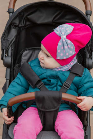 Little girl sitting in a baby carriage on the street