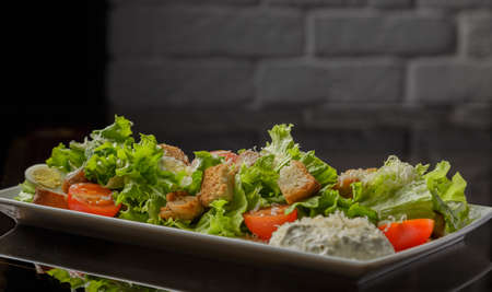 Caesar salad on a white plate and a glass backgroundの写真素材