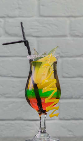 Glass with a cocktail on a glass table and a brick background