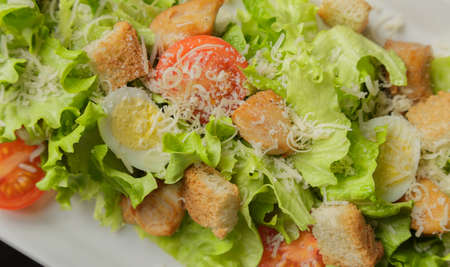Caesar salad on a white plate and a glass backgroundの写真素材