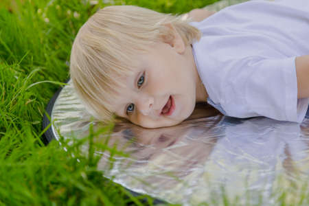 Happy little boy on a green lawn in a park.の写真素材