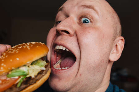 The eating of a hamburger by a man with a terrible expressionの写真素材