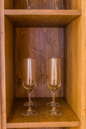 Glass wine glasses on a wooden shelf.の写真素材