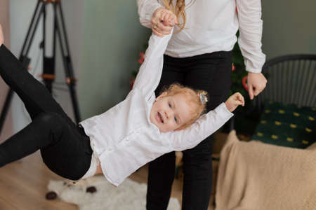 Happy mom swinging a little daughter in her arms.の写真素材