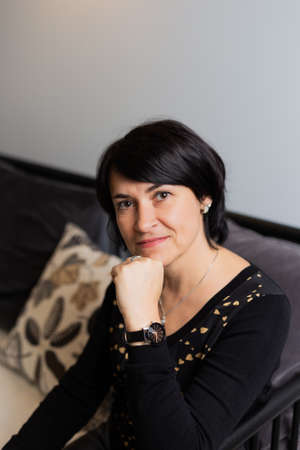 Beautiful woman 50 years old on a modern sofa. Woman portrait.の写真素材