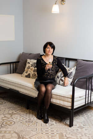 Beautiful woman 50 years old on a modern sofa. Woman portrait.の写真素材