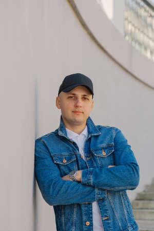 Handsome stylish man in a baseball cap on a concrete staircase.
