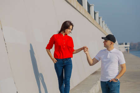 Happy lovers walk along the promenade holding hands.