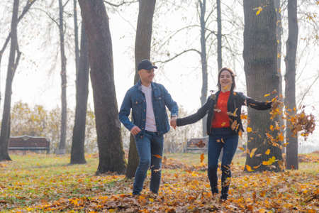 Happy lovers in yellow leaves in the autumn in the park.の写真素材