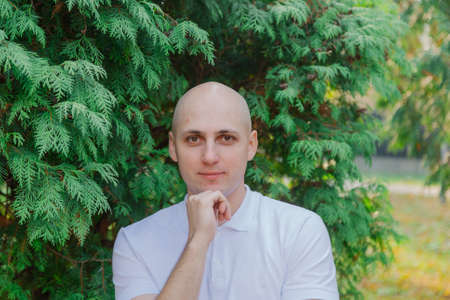 Handsome happy man near thuja tree in autumn weather.の写真素材