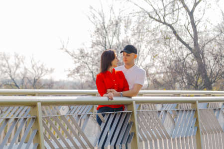 Happy young lovers stand on the iron bridge in autumn weather.