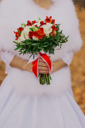 Beautiful happy bride with a wedding bouquet in the forest in autumnの写真素材