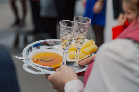 Adult woman holds honey cheese and champagne glassesの写真素材