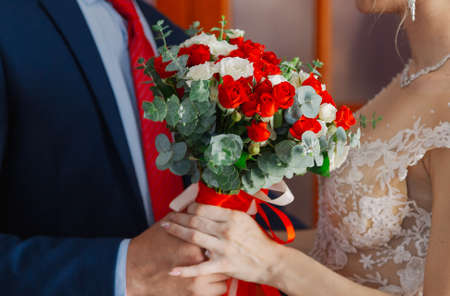 Young and happy bride and groom holding a wedding bouquet in their hands.の写真素材