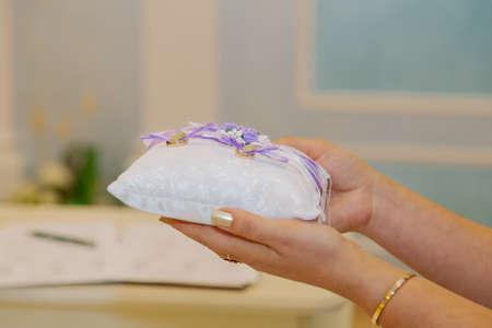 Gold wedding rings on a small pillow.の写真素材