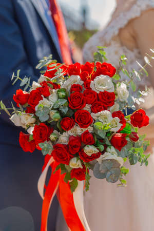 Young and happy bride and groom holding a wedding bouquet in their hands.の写真素材