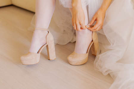 Young bride closes shoes on a happy wedding day.の写真素材
