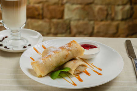 Freshly made pancakes with jam and sour cream.