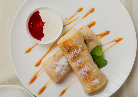 Freshly made pancakes with jam and sour cream.