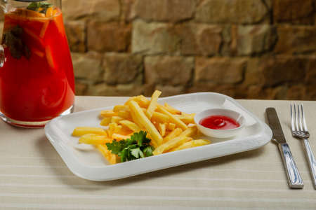 Fresh fried potatoes on a white plate with tomato sauce.の写真素材